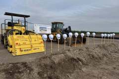 a line of shovels and hard hats are presented in front of large construction equipment at the ground breaking ceremony for Rye Ranch Elementary School in Parrish Florida