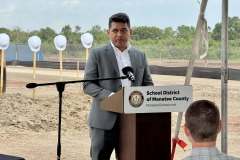 a gentleman in a grey suit speaks at the lectern during the ground breaking ceremony for Rye Ranch Elementary School in Parrish Florida