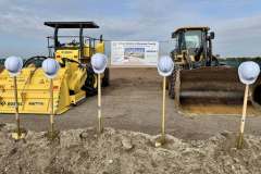 a line of shovels and hard hats are presented in front of large construction equipment at the ground breaking ceremony for Rye Ranch Elementary School in Parrish Florida