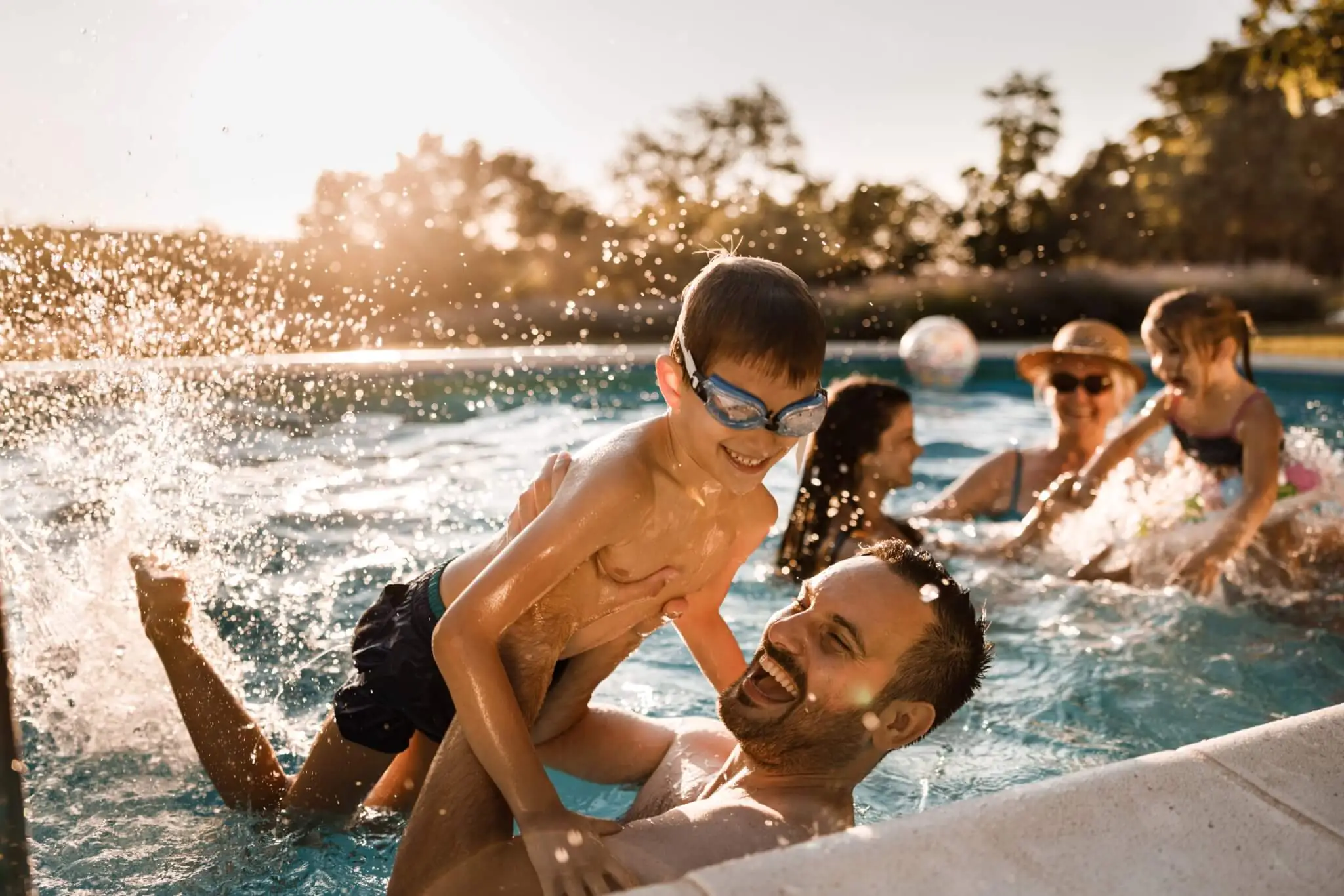 Playful father having fun with his small boy during family's summer day in the swimming pool.