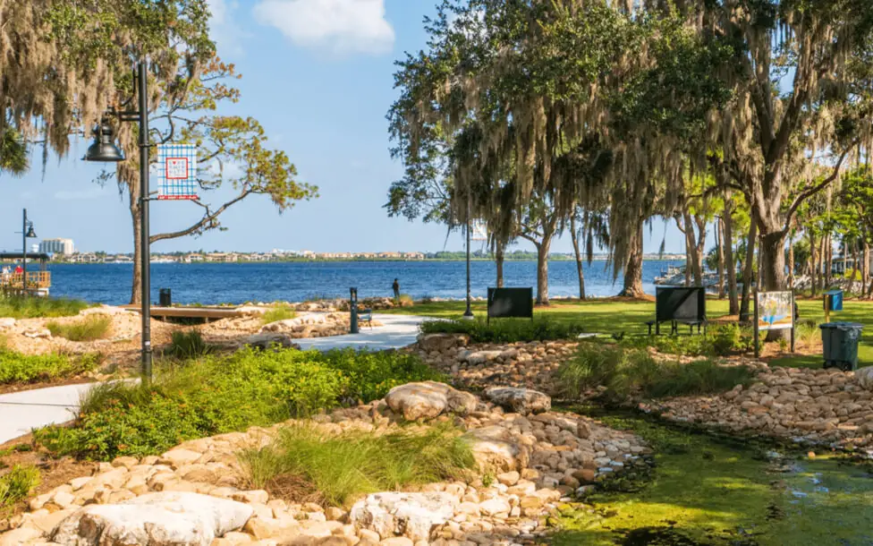 sunny day view of a stream surrounded by rocks and landscaping with a sidewalk leading to a broad waterfront at Manatee Mineral Springs Park - a hidden gem near Parrish Florida
