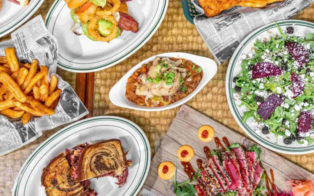 overhead view of an assortment of menu items - Reuben sandwich, French fries, ahi tuna, beet salad, and more - from The Freckled Fin, a hidden gem near Parrish Florida